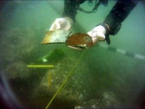 Here a diver holds recently excavated stoneware sherds from the Anniversary Wreck. The sherds help narrow the time frame of the wreck to sometime between 1750 and 1820. 
